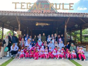 Tulungagung, 1 September 2023 - Sebuah momen tak terlupakan terjadi di Desa Bono, Kecamatan Boyolangu, Tulungagung, di mana anak-anak Paud Al Azhaar secara antusias belajar proses pembuatan jenang tradisional dari seorang ahli, Pak Lasimun, yang terkenal tidak hanya di kabupaten Tulungagung tetapi juga secara nasional. Kegiatan ini menjadi salah satu bentuk pembelajaran life skill yang berharga bagi 30 anak yang terdiri dari kelas B1 dan B2 Paud Al Azhaar Tulungagung.
Pak Lasimun, seorang yang berpengalaman dalam pembuatan jenang tradisional, membuka pintu rumahnya dan hatinya untuk berbagi pengetahuan kepada generasi muda. Dalam pelajarannya, ia menjelaskan bahwa pembuatan jenang melibatkan tiga bahan utama: tepung beras, kelapa, dan gula merah. Proses memasaknya memerlukan kesabaran, dengan waktu masak selama 6 jam yang memerlukan pengadukan kontinu. Anak-anak Paud Al Azhaar dengan mata berbinar-binar mendengarkan penjelasan detail ini.
"Kegiatan ini sangat berharga bagi anak-anak kami," kata Ustadzah Ririn Nurnaningsih, guru pendamping yang memimpin rombongan. "Mereka tidak hanya belajar tentang cara membuat jenang tradisional, tetapi juga pentingnya kesabaran dan ketelatenan dalam pekerjaan. Ini adalah pelajaran life skill yang akan berguna dalam kehidupan sehari-hari mereka."
Guru pendamping sebanyak 6 orang dengan penuh semangat membantu anak-anak dalam proses belajar. Mereka juga mendapatkan kesempatan untuk mengajarkan cara membungkus jenang dengan kertas pembungkus yang benar dan ciamik. Keahlian ini juga dianggap penting dalam melestarikan budaya lokal.
Bu Nur Hayati, Kepala Sekolah Paud Al Azhaar Tulungagung, tak hanya memberangkatkan rombongan, tetapi juga ikut ambil bagian dalam kegiatan ini. Beliau mengungkapkan, "Kami sangat bangga dengan semangat anak-anak kami dalam belajar dan berpartisipasi dalam kegiatan ini. Ini adalah salah satu cara kami mengajarkan mereka tentang nilai-nilai kearifan lokal dan pentingnya berbagi pengetahuan dengan masyarakat sekitar."
Kegiatan ini merupakan contoh nyata bagaimana pendidikan tidak hanya terbatas pada kelas, tetapi juga melibatkan interaksi dengan komunitas dan budaya setempat. Anak-anak Paud Al Azhaar Tulungagung membawa pulang pengalaman berharga dan keterampilan baru yang akan membantu mereka tumbuh menjadi generasi yang berpenghargaan terhadap tradisi dan memiliki keterampilan yang bermanfaat dalam kehidupan sehari-hari.
Kami berharap kegiatan seperti ini akan terus berlanjut untuk mendukung pembelajaran yang beragam dan pembentukan karakter anak-anak di Paud Al Azhaar Tulungagung. Semoga mereka terus termotivasi untuk belajar dan berbagi dengan masyarakat sekitar.
Dengan demikian, kegiatan belajar pembuatan jenang tradisional bersama Pak Lasimun di Desa Bono, Tulungagung, tidak hanya memberikan pengetahuan tentang warisan budaya lokal tetapi juga memupuk semangat berbagi pengetahuan dan keterampilan dalam generasi muda. Semoga anak-anak ini terus tumbuh menjadi individu yang berharga bagi masyarakat Tulungagung dan Indonesia secara keseluruhan.
